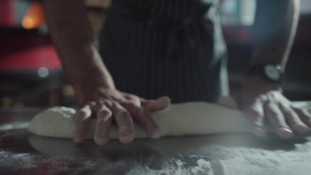 Slow motion. The baker throws the dough on the table with flour.