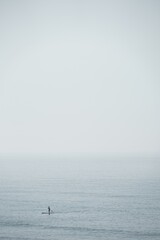 stand up paddler on ocean on foggy day