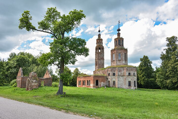 an abandoned dilapidated church, overgrown with grass against the background of the sky, surrounded by greenery