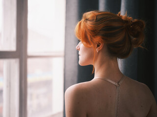 Portrait of a redhead woman near the window