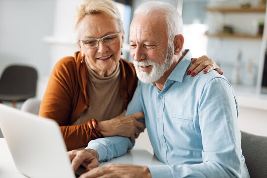 Happy mature couple using laptop at home