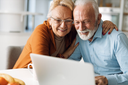 Embraced senior couple using laptop at home