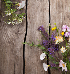 Wild flowers on old grunge wooden background (chamomile lupine dandelions thyme mint bells rape)