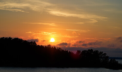 Beautiful orange colored sunset over a forest by a lake