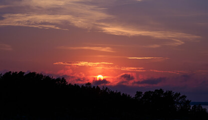 Beautiful orange colored sunset over a forest by a lake