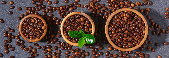 Roasted brown coffee beans on a gray background. Coffee beans in wooden bowls. Top view.