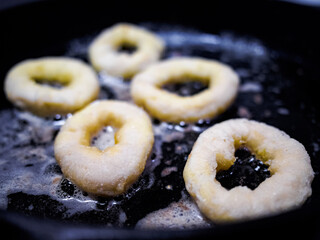 Close up overhead shot of breaded calamari rings in the frying pan