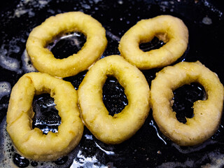 Close up overhead shot of breaded calamari rings in the frying pan