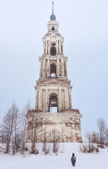A bell tower in the middle of a frozen lake,close-up from below , a child walking from the back