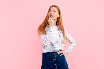 Young woman thinking about idea looking up over pink background