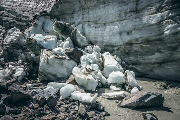 Scenic landscape with powerful mountain river beginning from glacier with ice chunks. Beautiful scenery with glacier at source of turbulent glacial river. Mountain river among moraines and ice blocks.