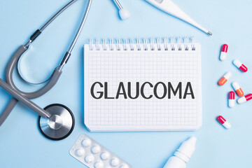 The word GLAUCOMA written on a white notepad on a blue background near a stethoscope, syringe, electronic thermometer and pills. Medical concept