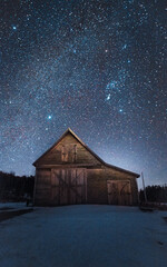 Old farm barn with a sky filled with stars on a cold winter night. © Josh
