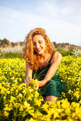 Young redhead girl in a beautiful field of yellow flowers in a green vintage dress