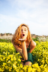 Young redhead girl in a beautiful field of yellow flowers in a green vintage dress