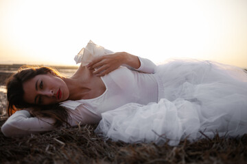 Girl dressed in tulle in a warm sunset on a straw background