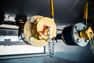 Truck with trailer, tank with flammable liquid, sunny day outside, metallic color container, blue sky with white clouds, gravel