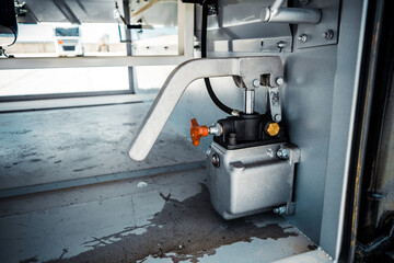 Truck with trailer, tank with flammable liquid, sunny day outside, metallic color container, blue sky with white clouds, gravel