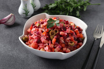 Salad Vinaigrette of beets, potatoes, carrots, olives, apples, onions and vegetable oil on dark gray background. Vegetarian food. Close-up