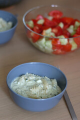 Two bowls of pasta with zucchini sauce and a bowl of cucumber and tomato salad. Selective focus.