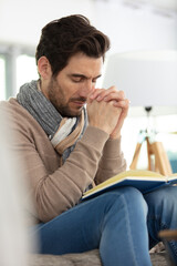 young man praying on wooden bible at home