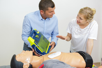 cpr practice of woman and man on cpr dummy outdoors