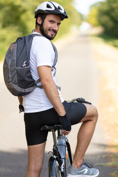 young man standing with bicycle wearing a backpack