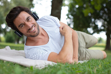 young man on the grass listening music on tablet