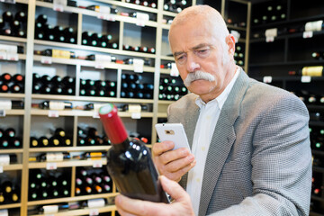 old man holding a good bottle of wine