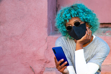 young black african american woman with mobile phone and mask on the street
