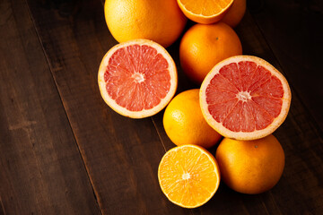 top view image of ripe orange and grapefruit slices and several whole oranges on brown rustic wooden table with copy space