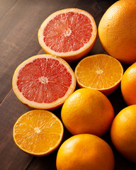 ripe orange and grapefruit slices and several whole oranges on brown rustic wooden table