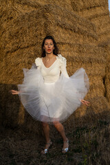 Girl dressed in tulle in a warm sunset on a straw background