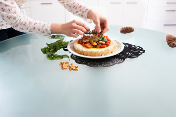 Woman's hands decorating a homemade vegetable cheesecake with cherry tomatoes.
