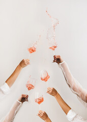 Female hands swirling glasses of rose wine making splashes - 421367096