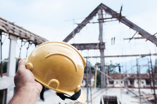 A Person Holding A Safety Helmet On A Construction Site