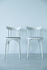 Two white chairs against a white wall