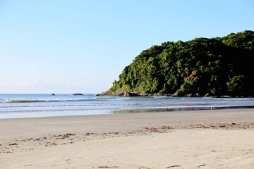 Fototapeta na wymiar Seascape with beach sand, calm waters, sea, and one island with tropical vegetation.