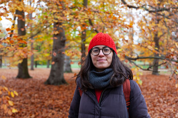 person in autumn park,woman in red hat smiling, woman in an autumn forest