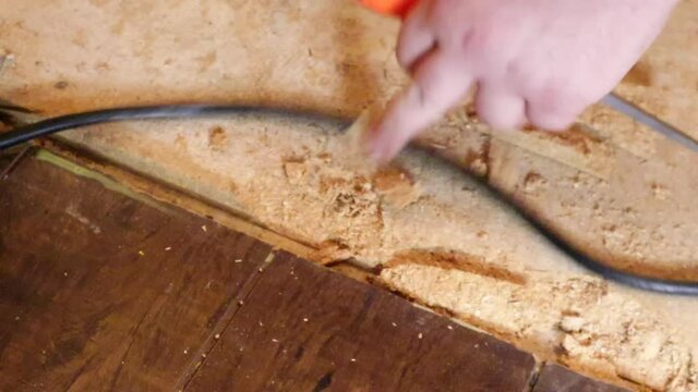 using a chisel and hammer to pry out old nails from subflooring