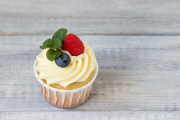 Delicious cupcake with butter cream, fresh raspberries, blueberries and mint.