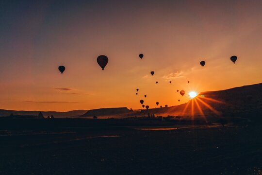 Hot Air Balloons Flying Over Land During Sunset
