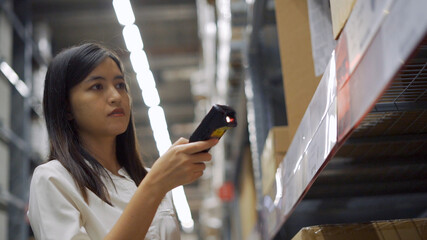 Female worker scanning products with barcode scanner in warehouse.