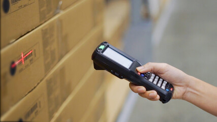 Close up hand scanning products with barcode scanner in warehouse. - obrazy, fototapety, plakaty