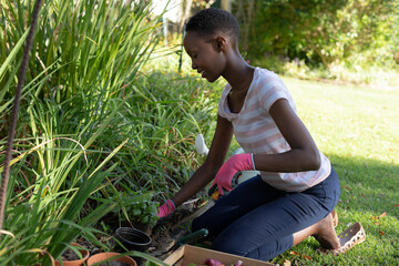 African american woman gardening and smiling on sunny garden terrace