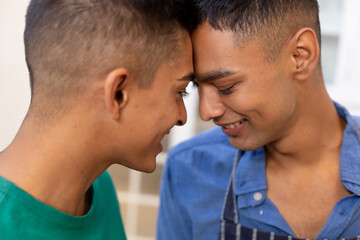 Diverse gay male couple looking at each other and smiling