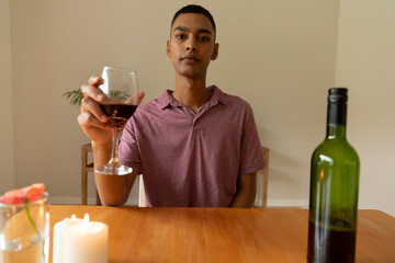 Portrait of mixed race man holding glass of red wine looking at camera