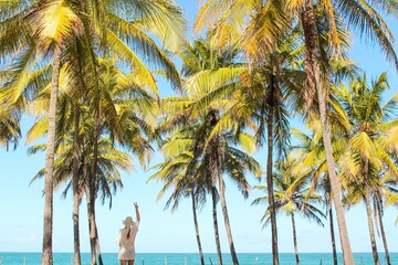 Mulher na praia com coqueiros