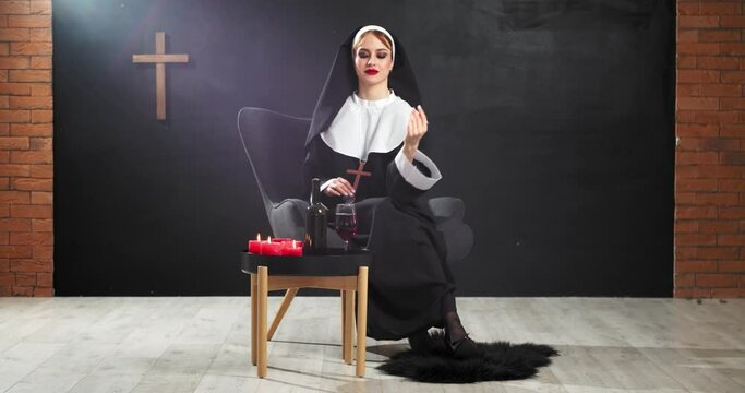 Sexy nun drinking wine on dark background