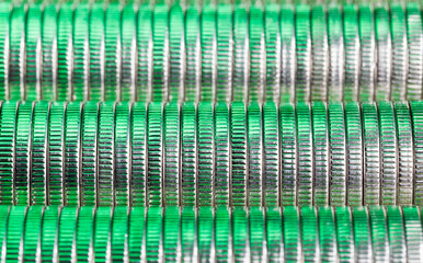 many round metal coins of silver color illuminated in green